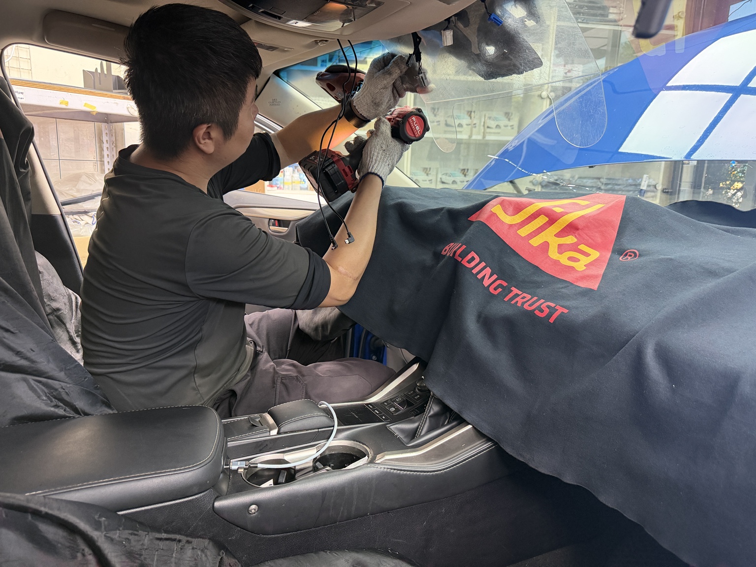 技師在做好內裝防護的車內，使用絞盤搭配線材拆卸前擋玻璃