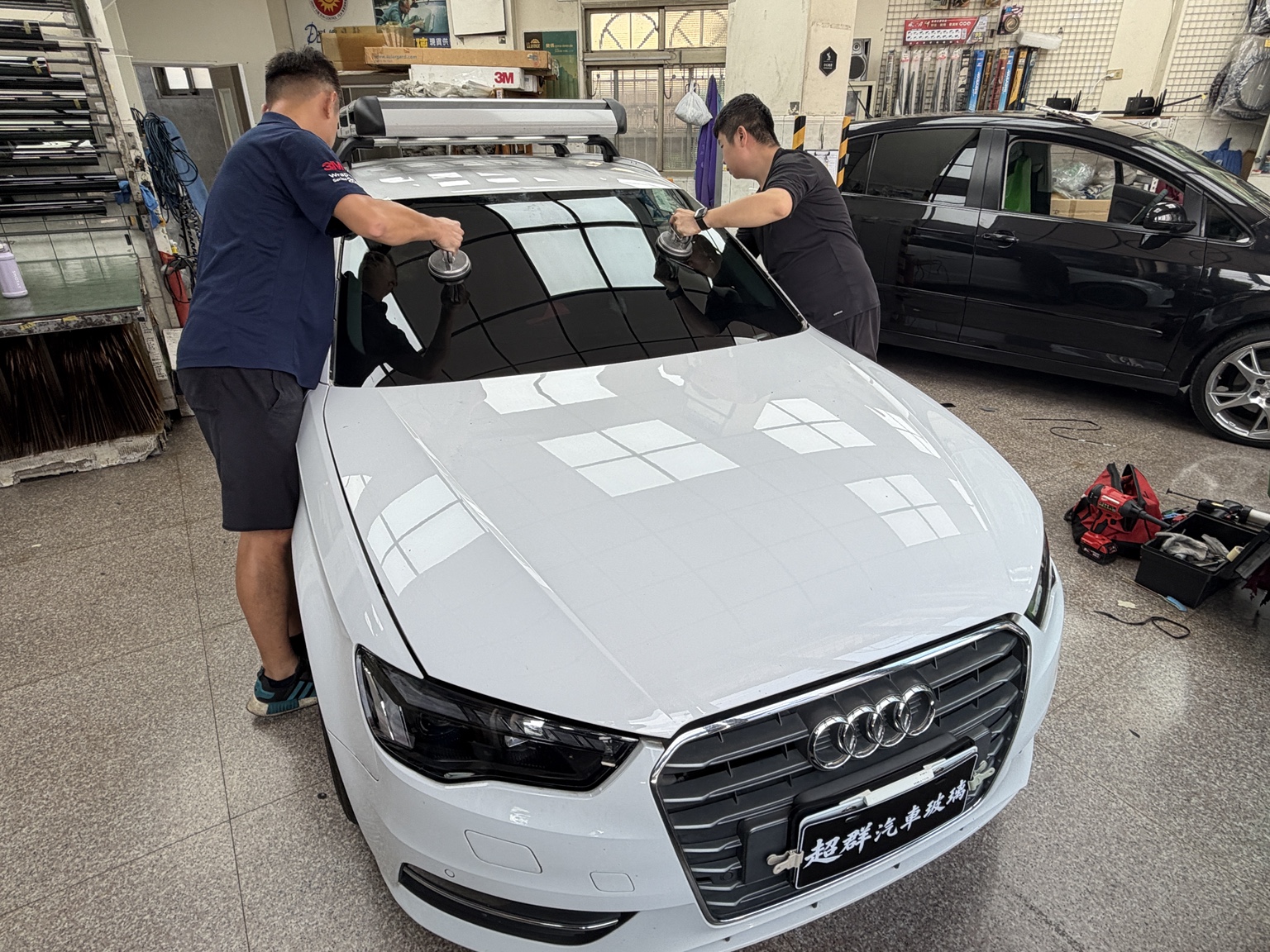 第二工作室內，兩位超群技師使用吸盤安裝 Audi 前擋玻璃
